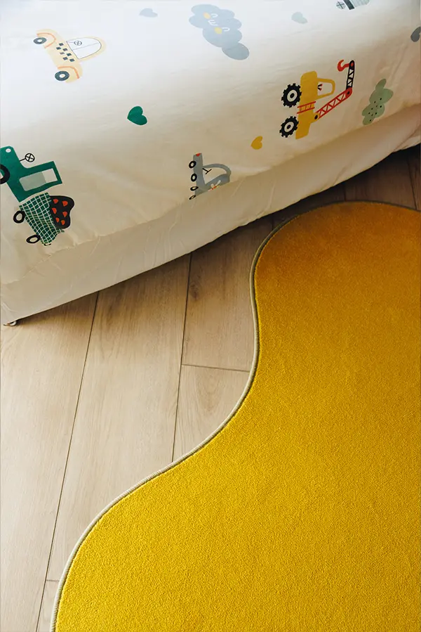 Yellow rug on the floor next to kids bed