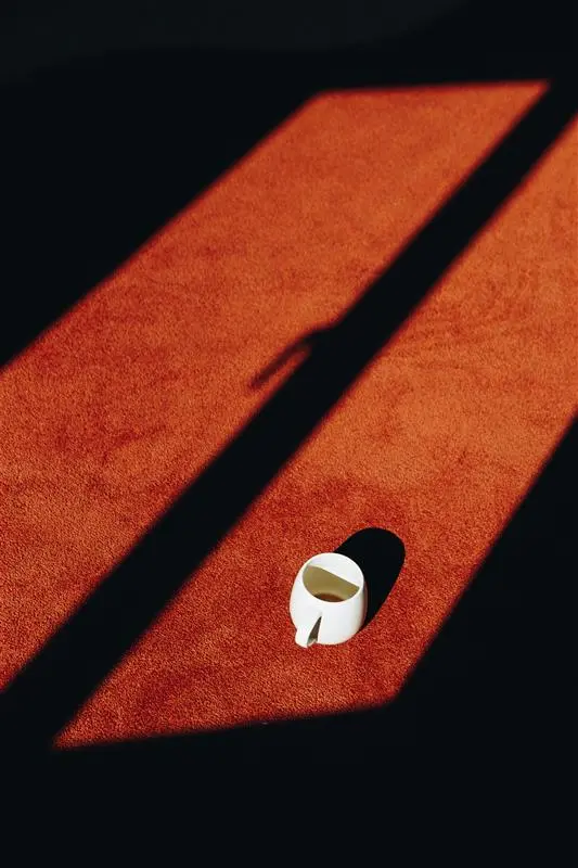 Orange carpet through window view with white cup